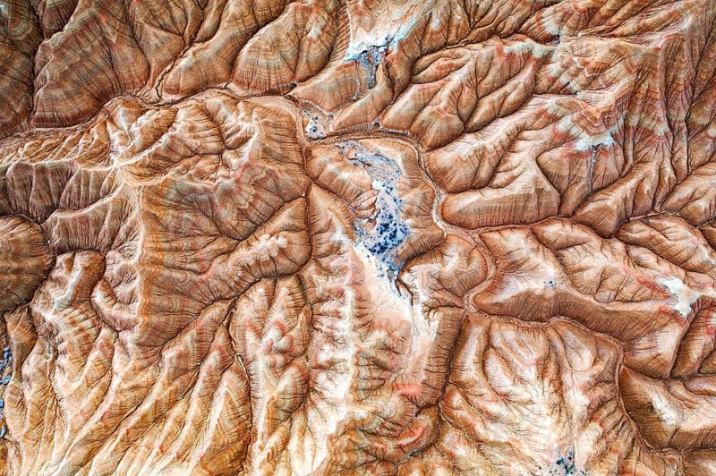 Aerial view of a rugged desert landscape with intricate patterns and natural formations The textures and shades create a striking visual of barren beauty and earthy tones