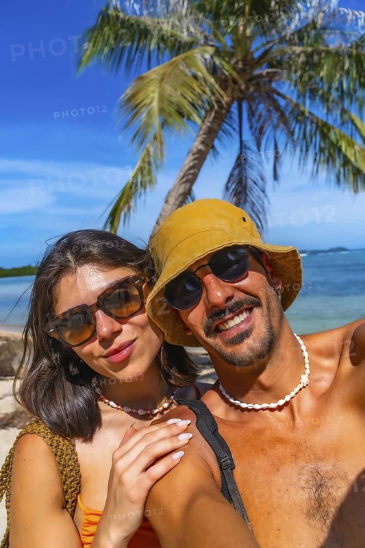 Happy couple taking a selfie on lakdayan beach, coron island, with palm trees and turquoise waters in the background during their philippines vacation