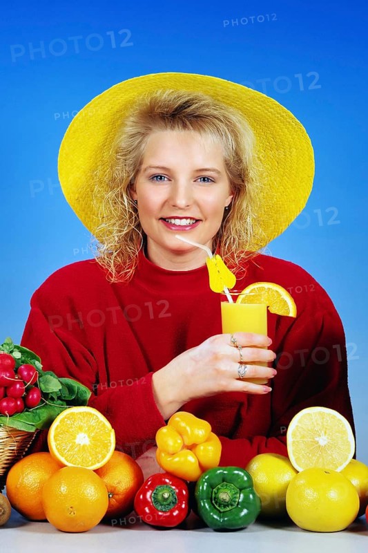 Young blonde woman drinking a glass of orange juice for breakfast, studio