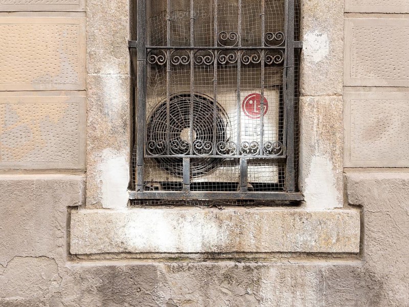 Air conditioning behind a window grille in the Barceloneta neighbourhood in Barcelona, Spain