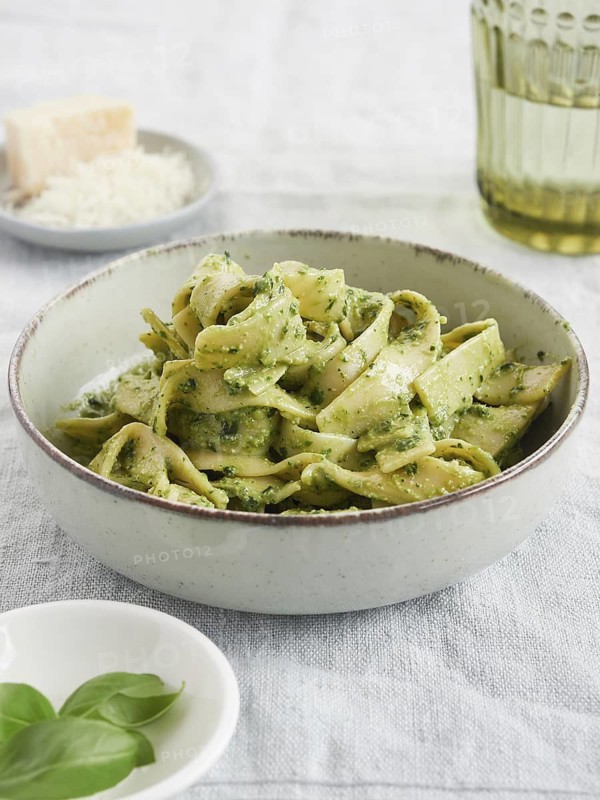 Close-up of green pasta dish, Tagliatelle with pesto with basil leaves and parmesan cheese. Traditional Italian food