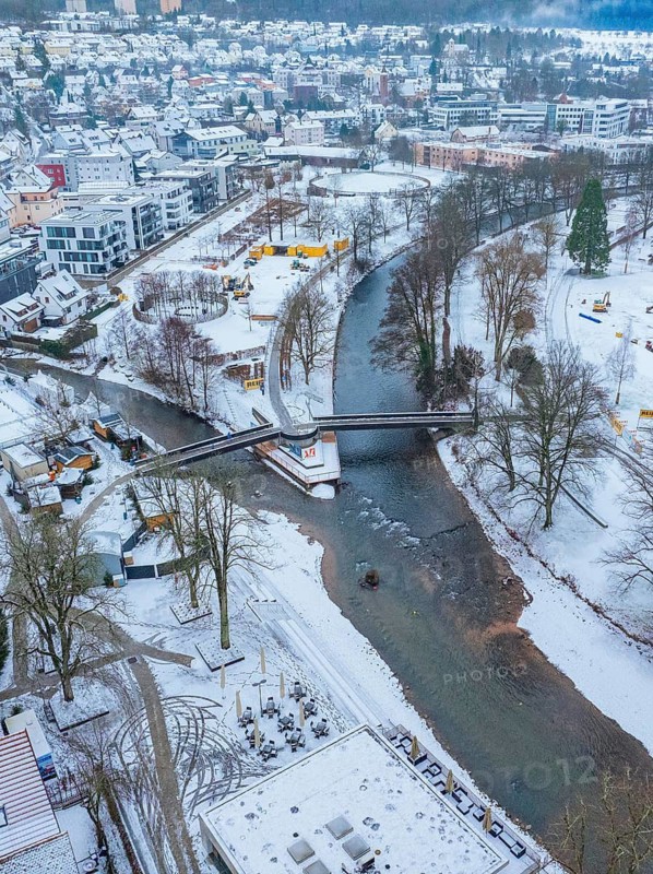 Town in winter with snow-covered river and bridge, surrounded by houses and trees, Nagold, Black Forest, Germany