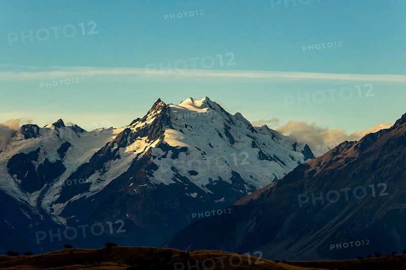 A breathtaking autumn view of Mount Cook in New Zealand with snow capped peaks and a clear blue sky, showcasing the majestic beauty of the mountains during the fall season
