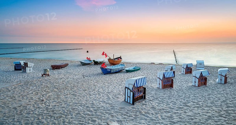 Beach chairs and fishing boats with red flags on fine sandy beach at sunrise, Baltic resort Kölpinsee, Usedom island, Mecklenburg-Western Pomerania, Germany