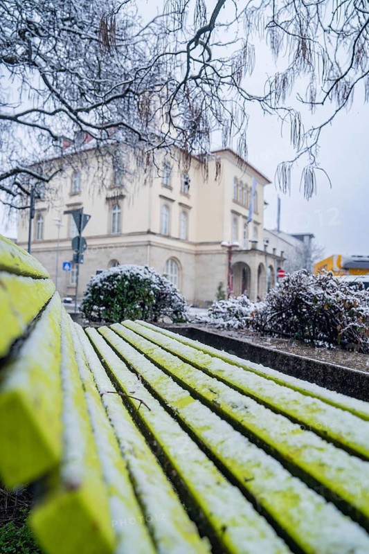 Snowy city view with park bench and traditional building in the background, Sindelfingen, Germany