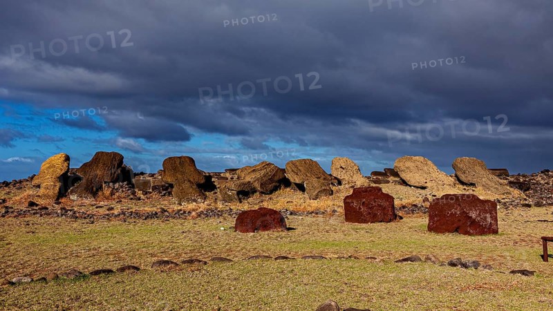 Fallen moai and reddish stones against a partly cloudy sky on Easter Island, the moai statues on Easter Island in the Pacific Ocean