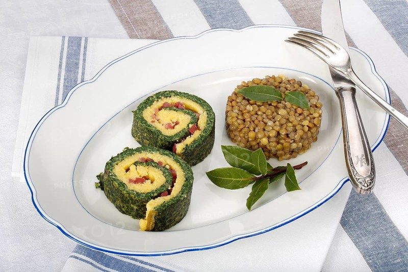 Southern German cuisine, polenta spinach roulade with alblentils served on serving platter, bay leaves, lentil vegetables, smoked meat, bacon cubes, healthy, food photography, studio, Germany