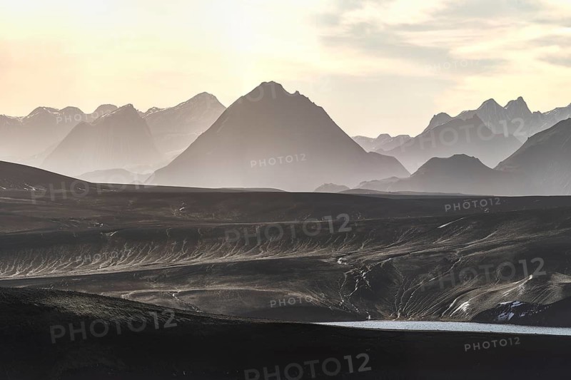 Captured at sunrise, this image showcases the breathtaking beauty of Iceland's highlands, featuring rugged mountains and vast open plains, bathed in a soft, ethereal light