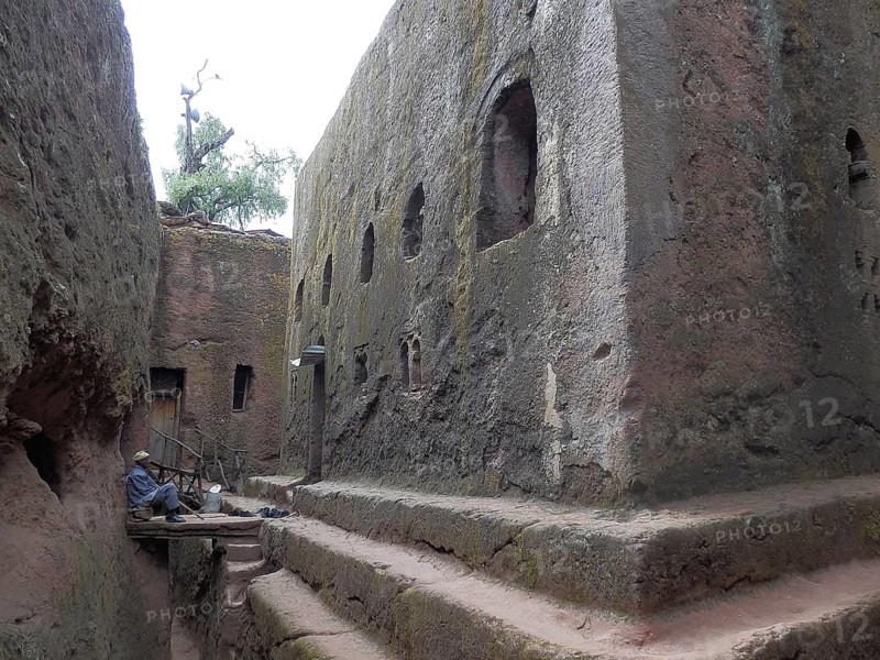 A man in traditional clothing sits on stone steps, UNESCO World Heritage Site, Lalibela Rock Church, Ethiopia