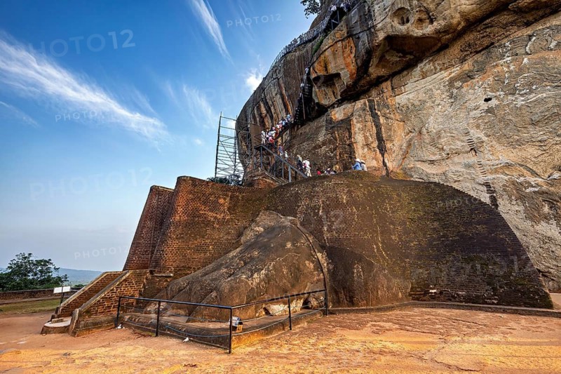 Massive rock structure with stairs and visitors, a historic architectural backdrop, The Lion Gate on Lion Rock near Sigiriya in Sri Lanka