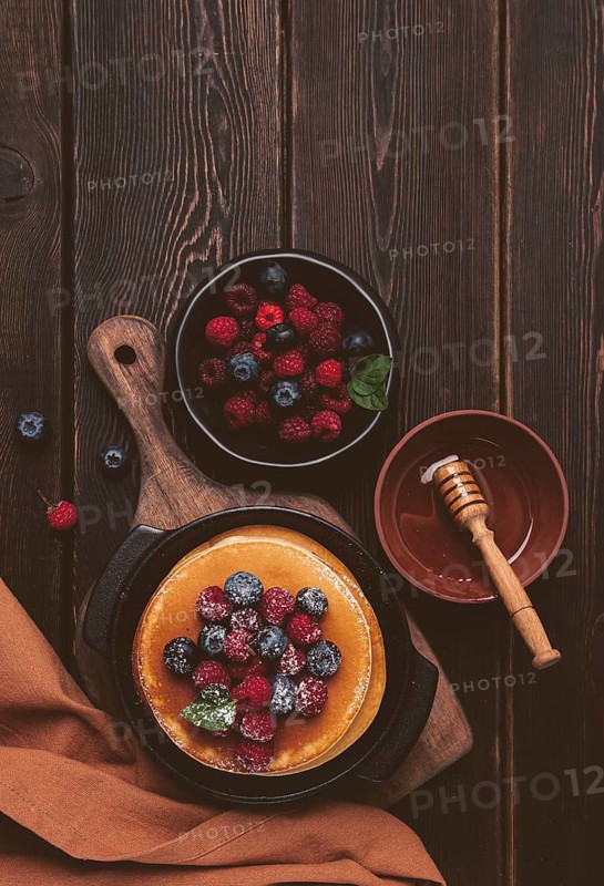 Breakfast, pancakes with berries and honey, top view, homemade, no people, on a wooden background