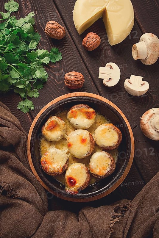 Traditional Georgian dish, appetizer, stuffed mushrooms, Sulguni cheese, baked in a Ketzi clay pan, on a wooden table, close-up, no people