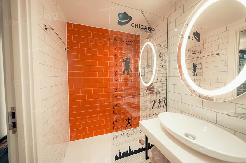 Modern bathroom with white and orange tiles, round illuminated mirror and musical theme, Ibis Styles Hotel, London, United Kingdom