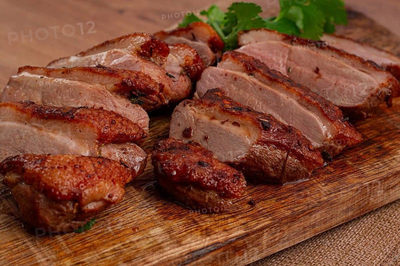 Roast duck breast, sliced, on a wooden chopping board, close-up, no people