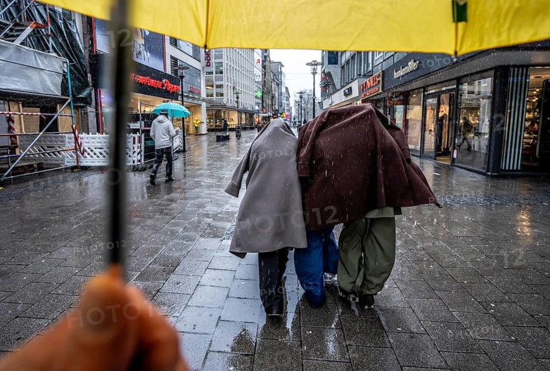 Passers-by in a pedestrian zone, Kettwiger Straße, young woman in rainy weather, without an umbrella, protecting themselves from the rain with coats and jackets, city center, Essen, North Rhine-Westphalia, Germany