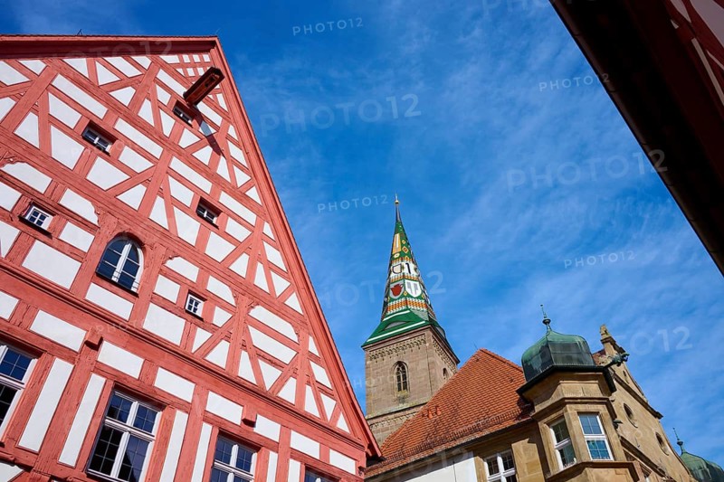 Close-up of a half-timbered house with a view of an ornate church tower in the background, Wolframs-Eschenbach, Ansbach district, Middle Franconia, Bavaria, Germany