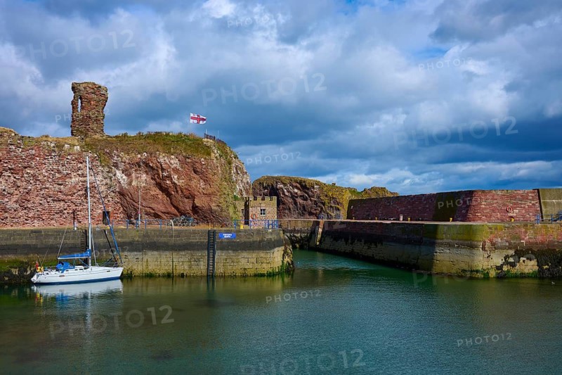 A harbour with a sailboat, an old tower and calm water under cloudy sky, Dunbar, East Lothian, Scotland, United Kingdom, Great Britain