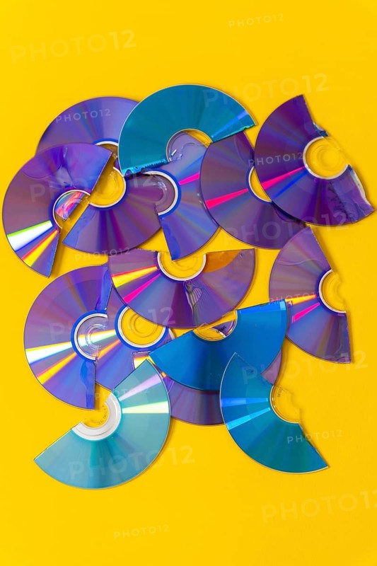 Top view of cut CDs and DVDs against a yellow background