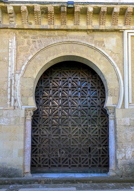 An artfully designed wooden archway with geometric pattern, Cathedral Mosque of Córdoba, Mezquita-Cathedral, An artfully decorated wooden door with an arabesque pattern sits in a massive stone archway, Cordoba, Andalusia, Spain
