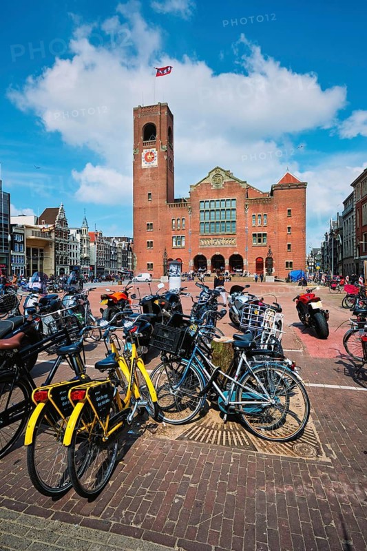 Amsterdam, Netherlands, May 7, 2017: Beursplein with parked bicycles motorcycles and Beurs van Berlage building former commodity exchange building now venue for concerts, exhibitions and conferences
