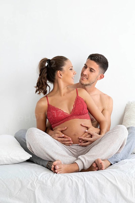 A joyful couple embracing as they cherish their pregnancy journey The expectant mother is in a red top, her partner holds her gently, conveying warmth and anticipation