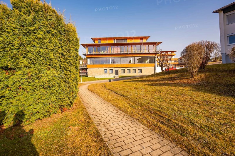 Well-maintained path leads to a modern building flanked by a hedge under a sunny sky, Hochgrat Clinic, Stiefenhofen, Bavaria, Germany