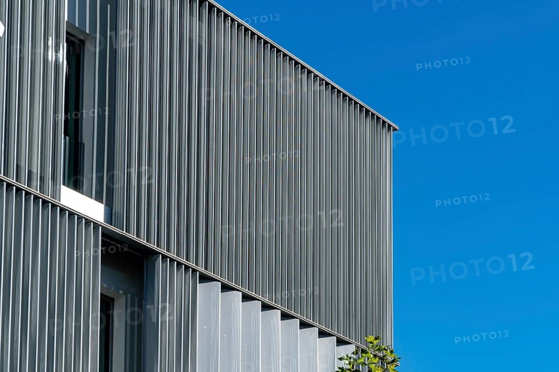 A crisp image highlighting the ribbed facade of a modern building, showcasing a juxtaposition of metal and glass against a vivid blue sky