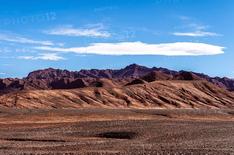 Panoramic view of the vibrant and rugged terrain of the Devil's Desert (Desierto del Diablo) in Salta, Argentina, showcasing unique geological formations under a bright blue sky