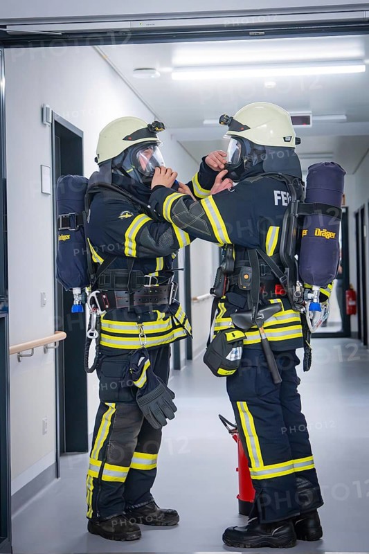 Two firefighters in full equipment communicate and prepare for deployment, fire brigade exercise on blue light day in the new Calw hospital, Germany