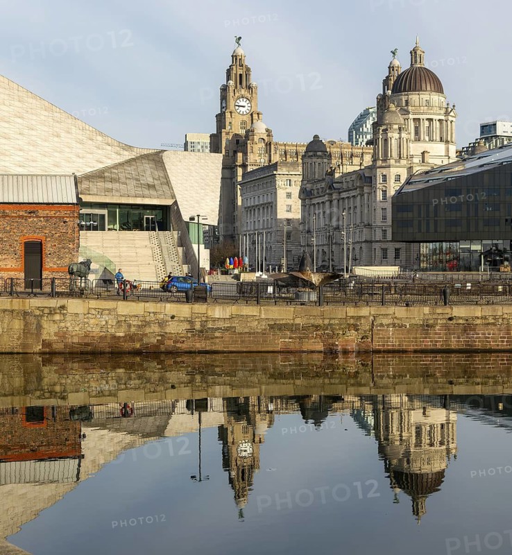 The Three Graces iconic waterfront landmark buildings reflected in water, Canning Dock, Liverpool, England, UK