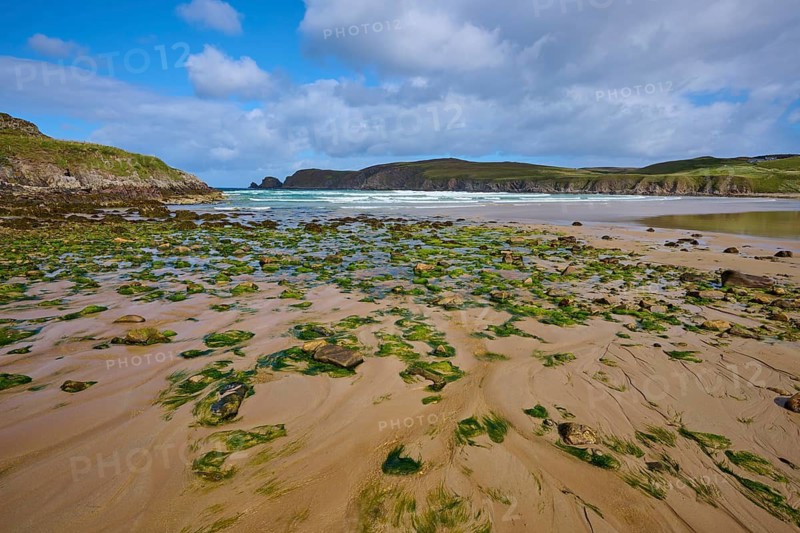A wide view of the algae-covered beach and rocks on the ocean horizon, Farr Bay, Bettyhill, Thurso, Scotland, United Kingdom, Great Britain