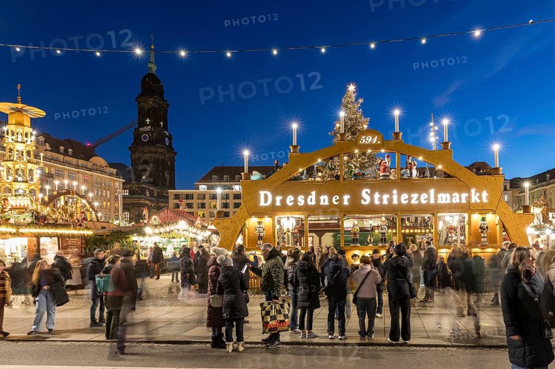 Large walk-in light arch at the entrance to Striezelmarkt, Germany's oldest Christmas market, with the Kreuzkirche tower in the background, Dresden, Saxony, Germany