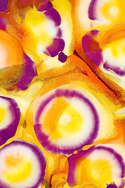 A vivid image showcasing swirling patterns of ink in rich shades of purple, yellow, and orange against a white backdrop. The colors blend dynamically, creating a fluid and visually engaging effect