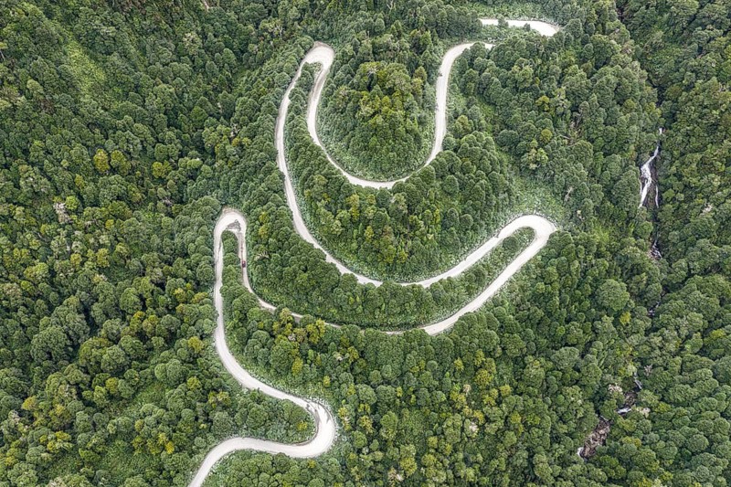Aerial view of a winding road (Carretera Austral) through dense forest, south of Puyuhuapi, Aysén Region, Chile