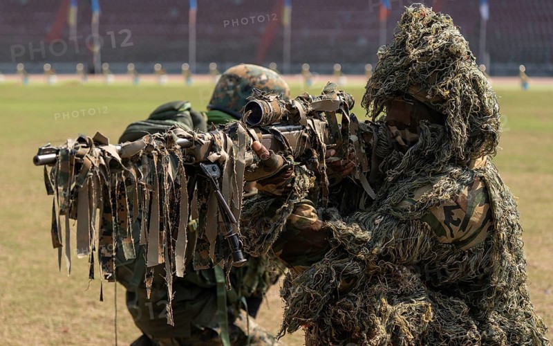 A camouflaged sniper of the Central Reserve Police Force takes aim during a tactical demonstration at the 87th Raising Day celebrations, on February 19, 2026 in Guwahati, India