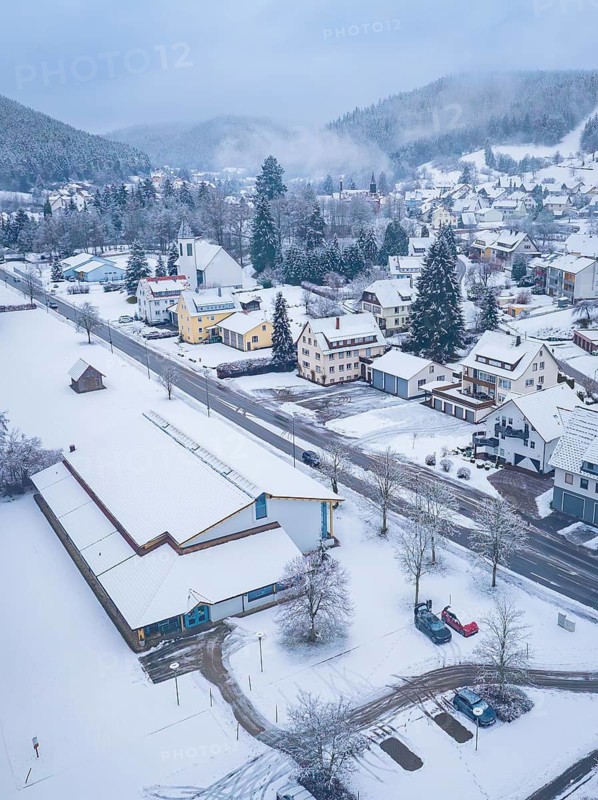 Snow-covered streets and houses of a village in wintry mountains. The scenery looks peaceful and cold, Enzklösterle, district of Calw, Black Forest, Germany