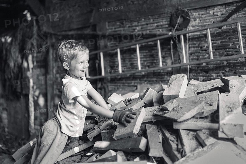 Little boy working in a shed with wood