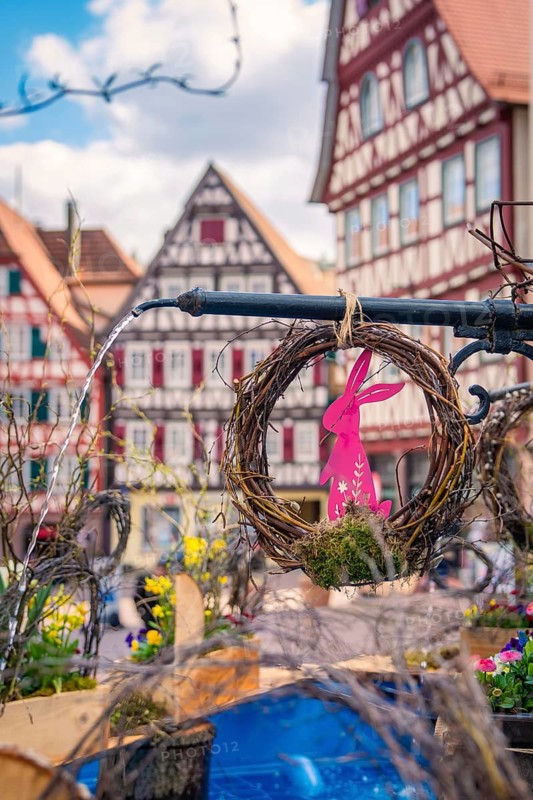 Colourful Easter wreaths with bunny motif in front of half-timbered houses in the background, Calw, Black Forest, Germany