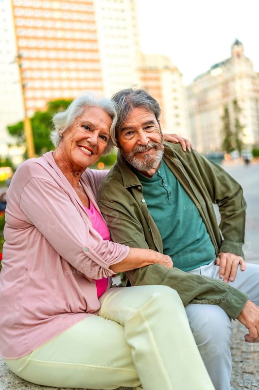Vertical portrait of a lovely mature couple sitting in an urban bench