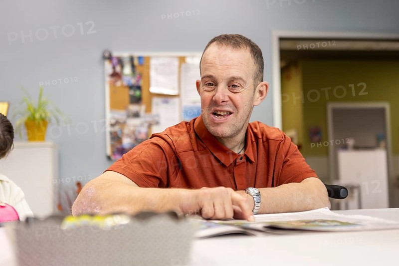 A cheerful man participates in activities at a day center for individuals with intellectual disabilities, fostering a supportive and engaging environment