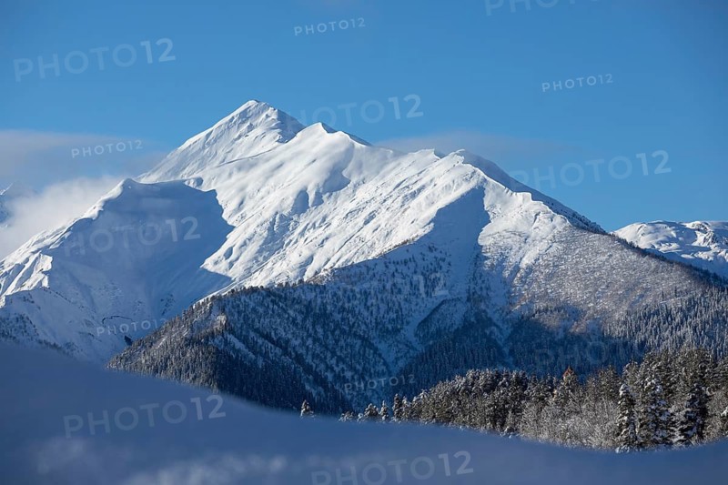 Captivating winter scene of snow-covered mountains under a clear blue sky, showcasing the beauty of nature in Georgia Perfect for conveying serenity and wilderness