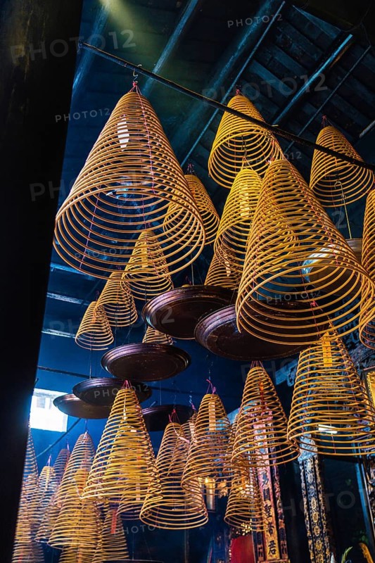Spiral incense hanging from the ceiling of a dark, atmospheric Taoist and Chinese Buddhist temple in Macau, creating a mystical ambiance