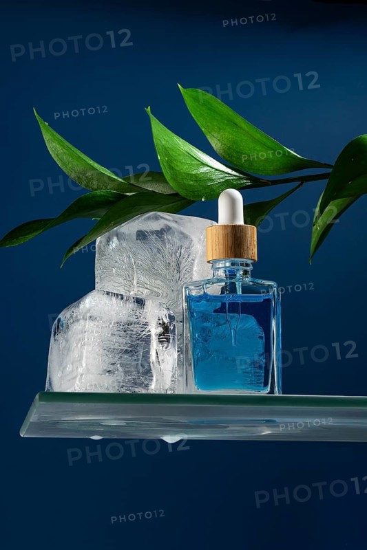 A refreshing face care serum or oil for men in a sleek dropper bottle. Designed for cooling effects, the pipette is prominently featured, set against a background of ice cubes