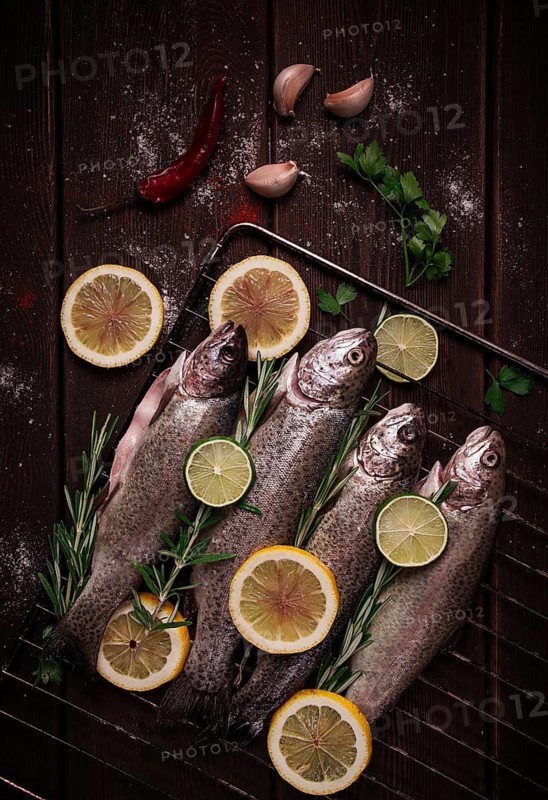 Raw rainbow trout, with lemon and herbs, on a wooden table, no people