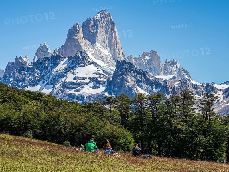 Hikers take a break, hiking trail to viewpoint Loma del Pliegue Tumbado, mountain range of Cerro Fitz Roy in the back, El Chalten, Argentina