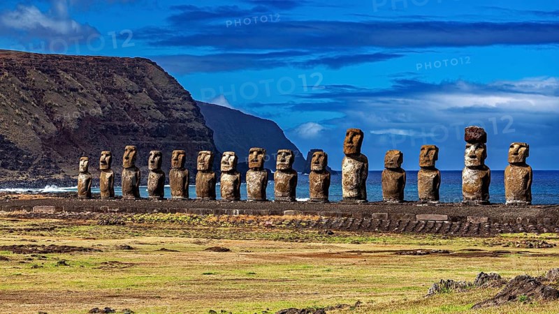Moai statues along a grassy coastline with rolling landscape in the background, The Moai statues on Easter Island in the Pacific Ocean