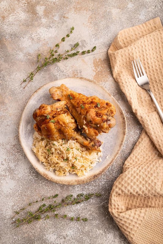 Fried Turkey Wing with spices and rice on brown concrete background and linen textile. top view, flat lay, close up
