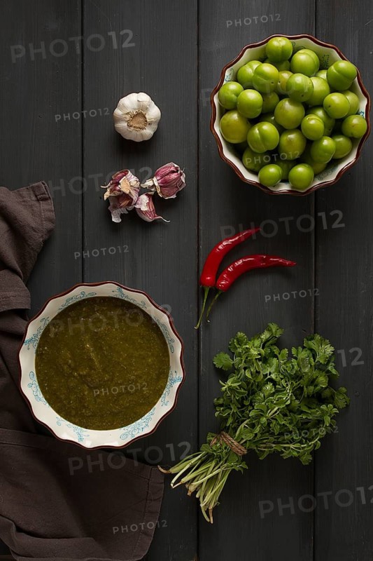 Tkemali sauce, traditional Georgian cuisine, green cherry plum, with ingredients for sauce, cilantro, mint, hot pepper, garlic, on a wooden table, close-up, rustic, food background, no people, selective focus, sauce, green sauce, tkemali, georgian cuisine, homemade