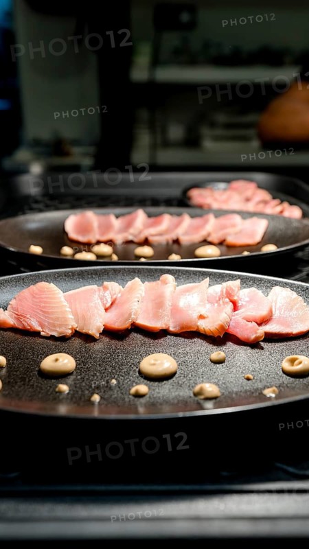 Thinly sliced seafood artfully arranged on a black plate with decorative sauce dots, perfect for a gourmet dining experience in a sophisticated restaurant setting