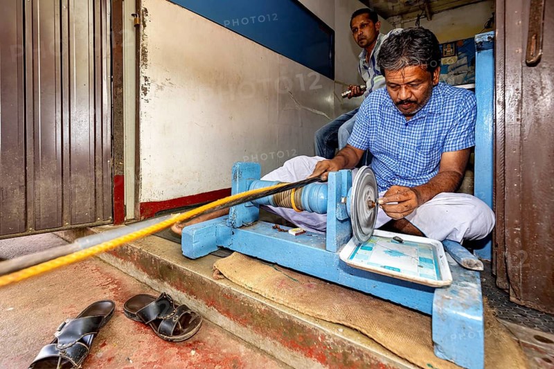 A man works concentratedly with a machine sitting on the floor, in a small room, The gemstone cutters in the city of Ratnapura in Sri Lanka